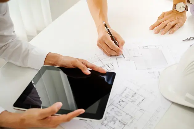 Architekten und Ingenieure diskutieren am Tisch mit einem Bauplan.